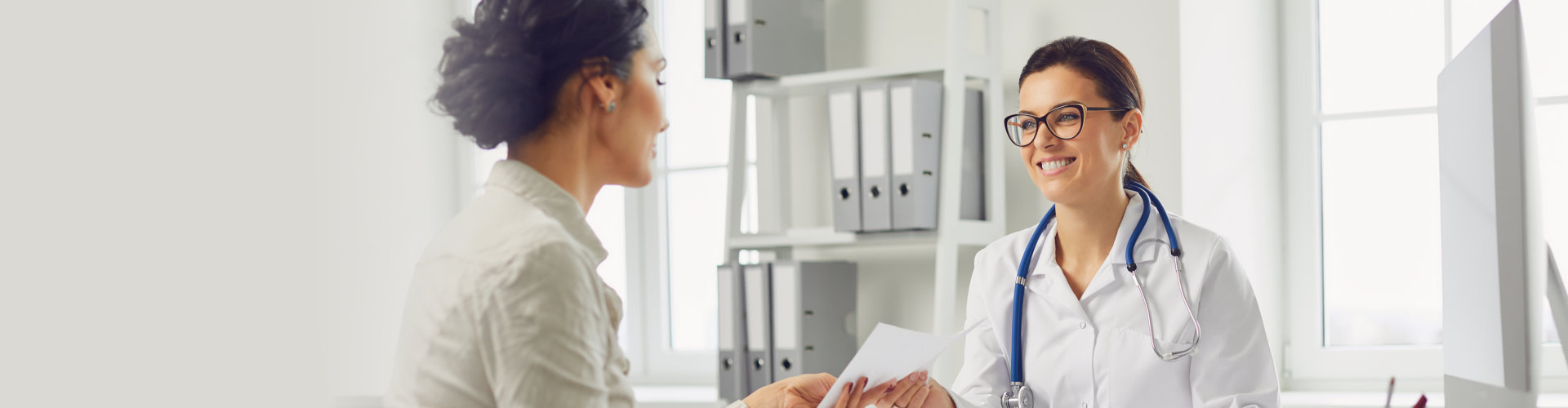 female patient at consultation with woman doctor sitting at table in office clinic